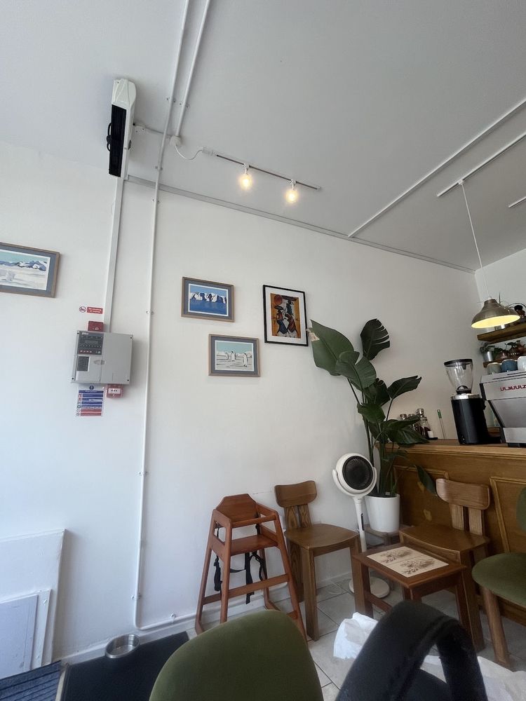 The cafe room at Oori, with white walls, framed pictures, wooden chairs and the coffee counter